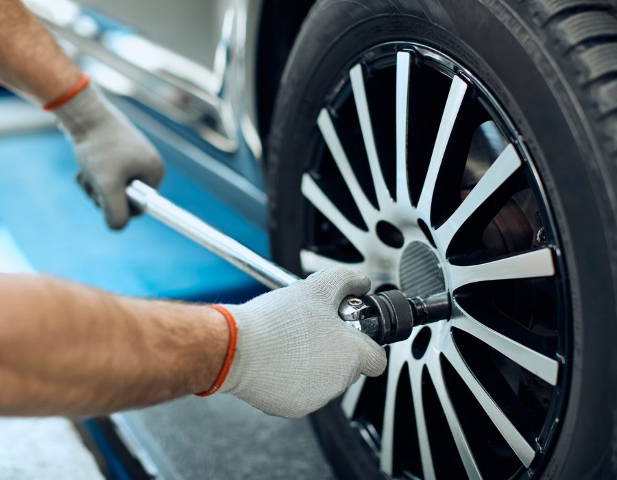 Close-up of mechanic changing car tire at auto repair shop.