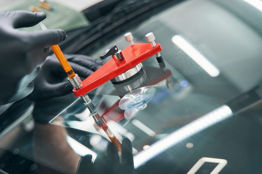 Serviceman in workshop fixing broken car window with vacuum filler. Professional auto glass repair